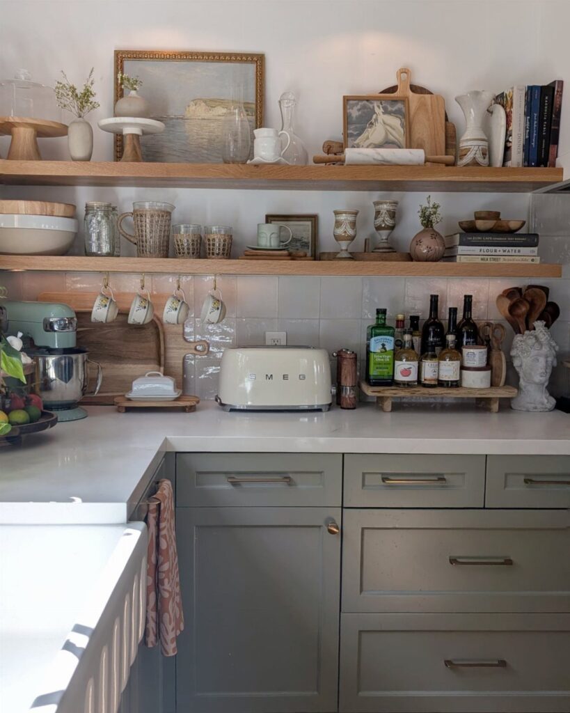 Wooden floating shelves holding various ceramic dishes, glassware, and decorative items against a white tiled wall.